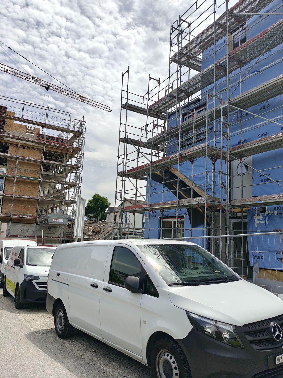 Gerüstbau mit Firmenfahrzeug an einem Neubau